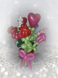 Balloons contorted to resemble wild flowers and roses, are wrapped in a magenta latex balloon twisted into a bow.